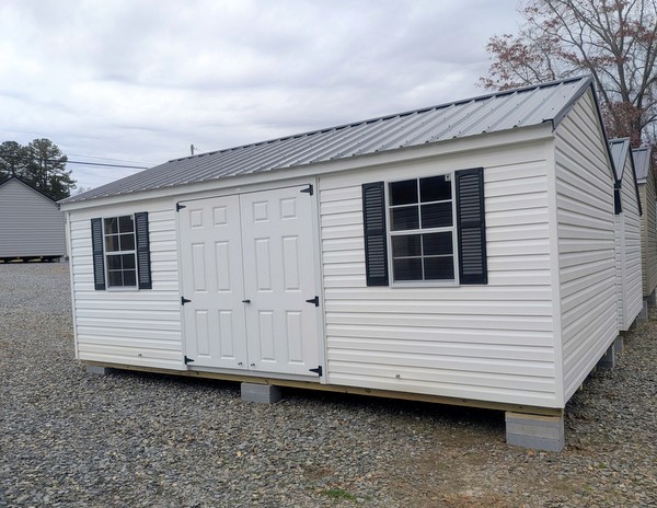 12x20 size vinyl a-roof style shed with white siding, white trim, black metal roof, black shutters. Has 6 foot fiber double doors and two windows.