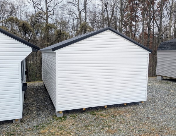 12x20 size vinyl a-roof style shed with white siding, white trim, black metal roof, black shutters. Has 6 foot fiber double doors and two windows.