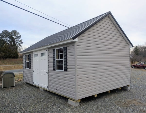 12 x 20 size vinyl garden style shed with flint siding, white trim, black metal roof, black shutters, fiber transom 6 foot double shed doors, two windows.