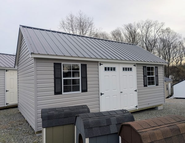 12 x 20 size vinyl garden style shed with flint siding, white trim, black metal roof, black shutters, fiber transom 6 foot double shed doors, two windows.