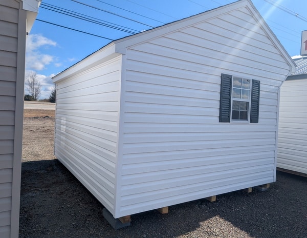 10x12 size vinyl carriage style shed with white siding, white trim, black architectural shingle roof, black shutters. has (1) 8' ridge vent, 6 foot fiber doors and two windows.