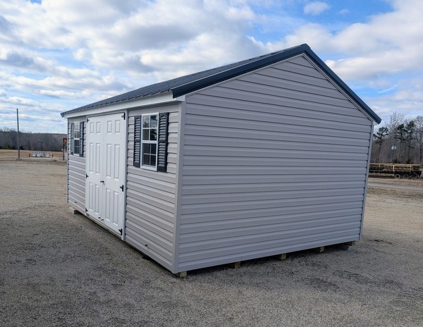 12x16 size vinyl a-roof style shed with flint siding, white trim, black metal roof, black shutters. Has 6 foot fiber double doors and two windows.