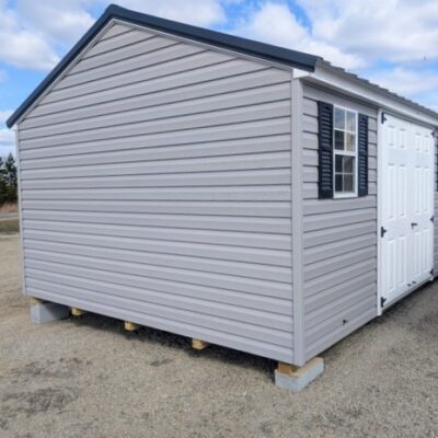 12x16 size vinyl a-roof style shed with flint siding, white trim, black metal roof, black shutters. Has 6 foot fiber double doors and two windows.