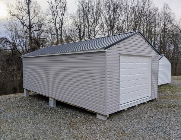 14 x 28 size vinyl a-roof garage style shed with flint siding, white trim, black metal roof, black shutters, 9x7 garage door, 6 foot fiber double doors with two windows.