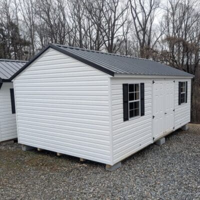 12x20 size vinyl a-roof style shed with white siding, white trim, black metal roof, black shutters. Has 6 foot fiber double doors and two windows.