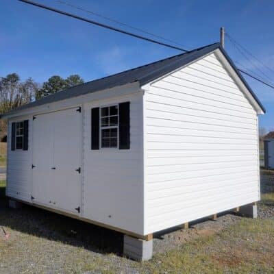 12x16 size vinyl classic roof style shed with white siding, white trim, black metal roof, black shutters. has 6' foot fiber double doors and two windows.