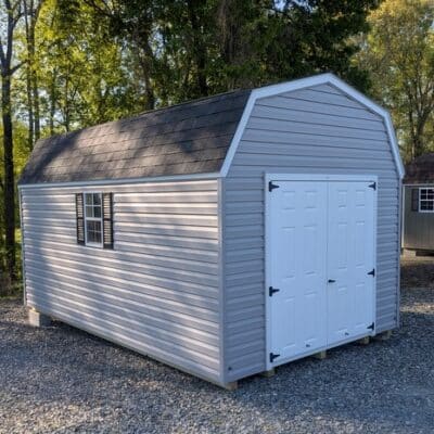 10x16 size vinyl high barn roof style shed with flint siding, white trim, black architectural shingle roof, black shutters. has 8' ridge vent, 6 foot fiber double doors and two windows.