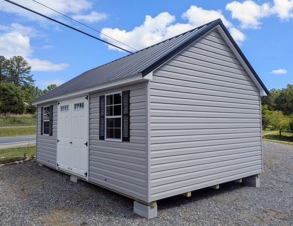 12 x 20 size vinyl garden style shed with flint siding, white trim, black metal roof, black shutters, fiber transom 6 foot double shed doors, two windows.