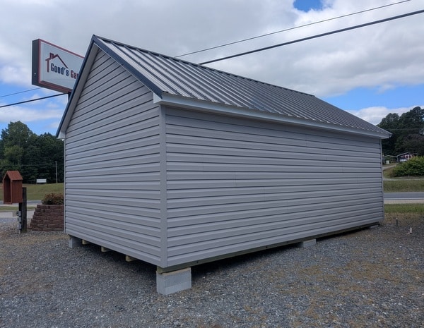 12 x 20 size vinyl garden style shed with flint siding, white trim, black metal roof, black shutters, fiber transom 6 foot double shed doors, two windows.