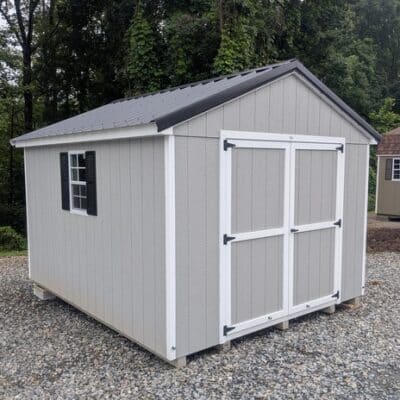 10 x 12 size painted a-roof style shed with gap gray siding, white trim, black metal roof, black shutters, ggs 6 foot doors, two windows.