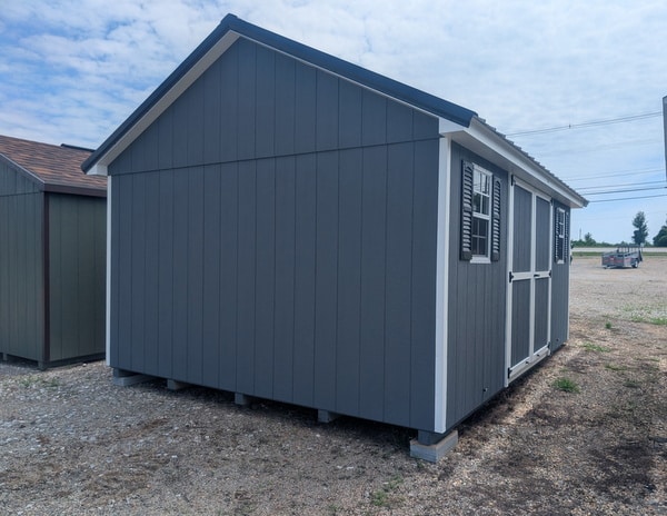 12 x 16 size painted classic style shed with gray siding, white trim, black metal roof, black shutters, ggs 6 foot double doors, two windows.