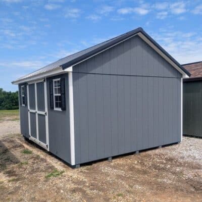 12 x 16 size painted classic style shed with gray siding, white trim, black metal roof, black shutters, ggs 6 foot double doors, two windows.