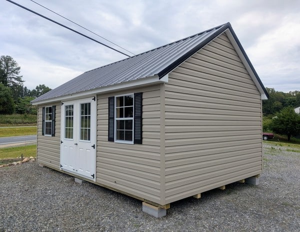 12 x 20 size vinyl garden style shed with clay siding, white trim, black metal roof, black shutters, fiber 9 lite 6 foot double shed doors, two windows.