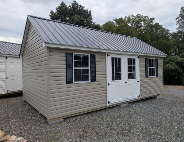 12 x 20 size vinyl garden style shed with clay siding, white trim, black metal roof, black shutters, fiber 9 lite 6 foot double shed doors, two windows.