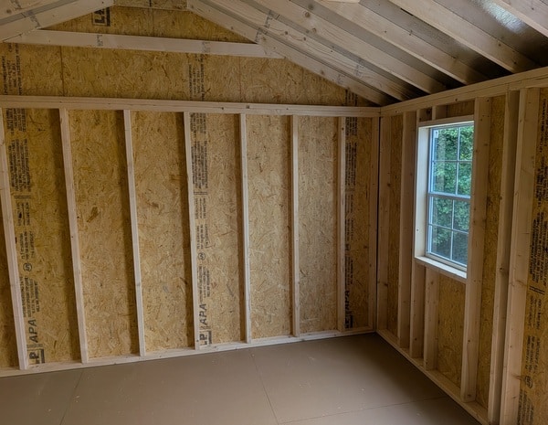 12x20 size vinyl a-roof style shed with clay siding, white trim, black metal roof, black shutters. Has 6 foot 2 plank double doors and two windows.