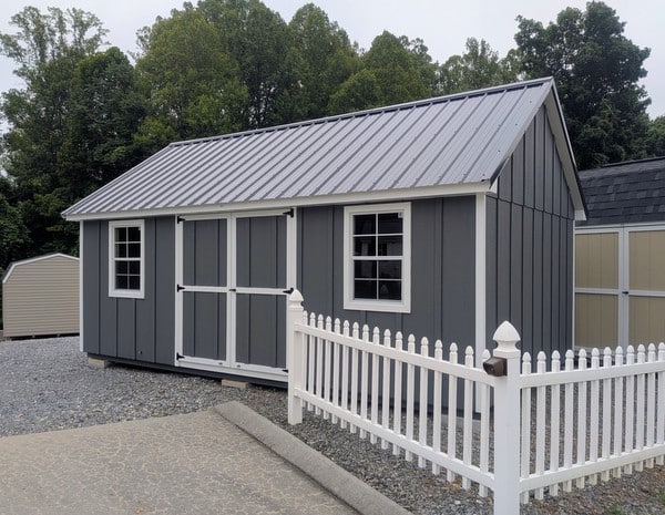 12 x 20 size painted garden board & batten style shed with gray board & batten siding, white trim, black metal roof, ggs 6 foot double doors, two windows.