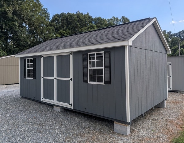 12 x 20 size painted classic style shed with gray siding, white trim, black architectural shingle roof, black shutters, (2) 10' ridge vents, ggs 6 foot double doors, two windows.