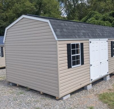 12x20 size vinyl high barn roof style shed with clay siding, white trim, black architectural shingle roof, black shutters. has (2) 10' ridge vents, fiber solid 6 foot double doors and two windows.