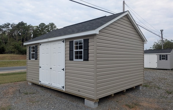 12x16 size vinyl classic style shed with clay siding, white trim, black architectural shingle roof, black shutters. has (1) 10' ridge vent, fiber solid 6 foot double doors and two windows