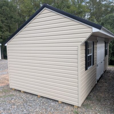 10x20 size vinyl carriage style shed with tan siding, white trim, black metal roof, black shutters. Has 6 foot fiber double doors and two windows.